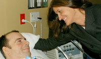 Woman leaning over man in hospital bed